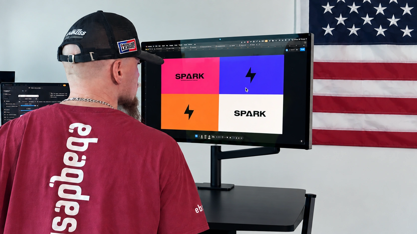Arek Dvornechuck at a clean studio desk with SPARK identity designs on screen and a US flag